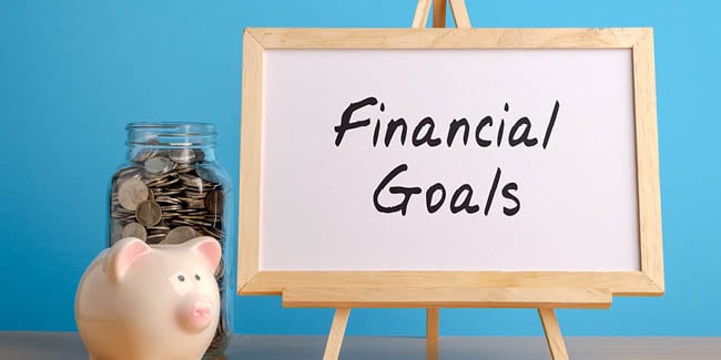Tiny pig and money jar with "Financial Goals" on a whiteboard
